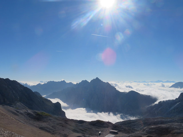 View from summit of Zugspitze. Blue skies and peaks of mountains sticking through clouds