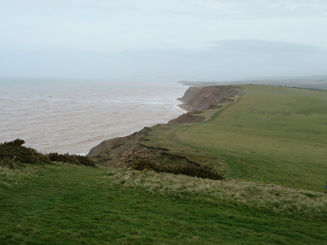 The cliffs on the South of the Isle of Wight Green hills, red stone cliffs. cloud over the sea