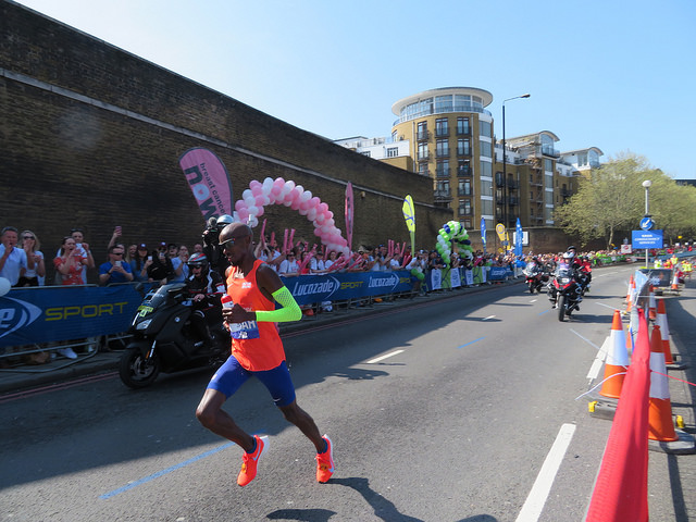 Mo Farah, in orange top and blue shorts, running the London marathon in April 2018