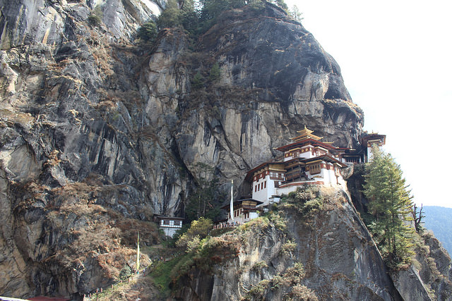 A red and white monastery on the side of a mountain in Bhutan