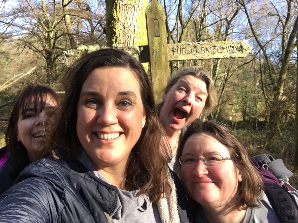 Four women grinning in the woods