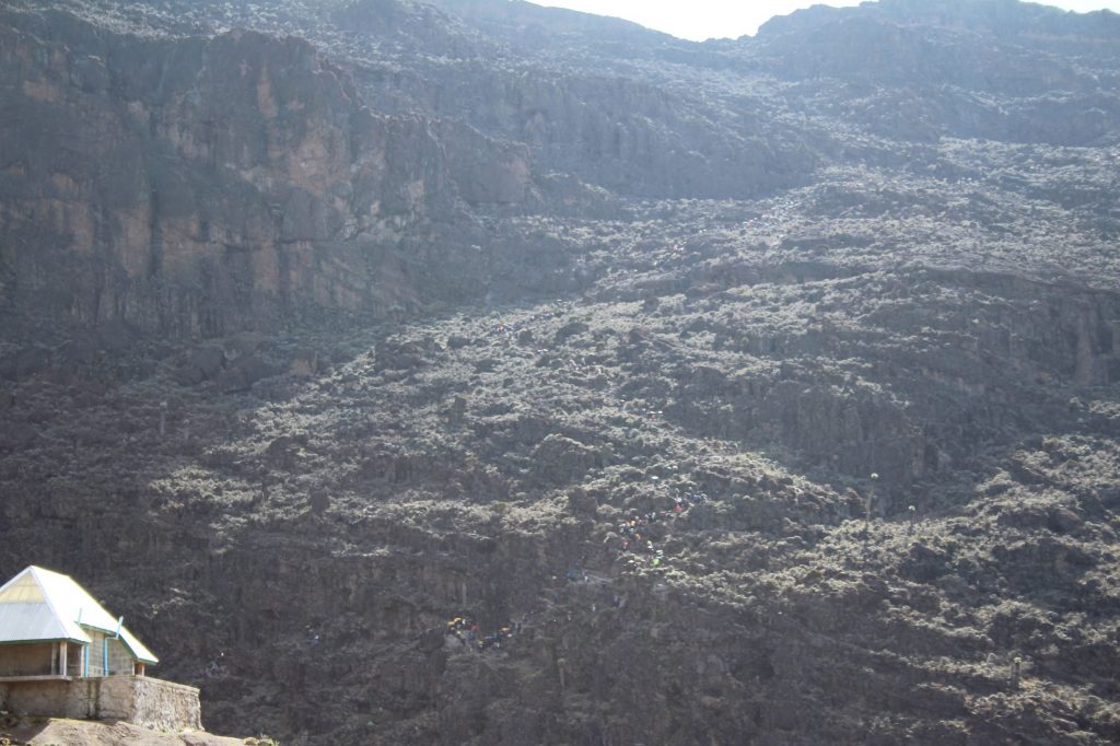 Cliff face, with a queue of people walking up the path