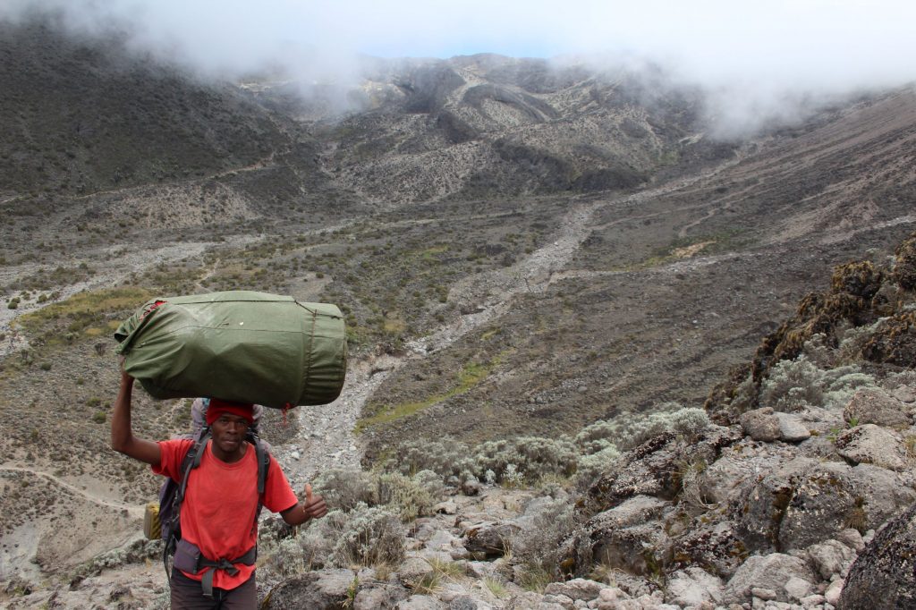 Looking down the path of the Baranco wall, with a poter carrying a load up the path