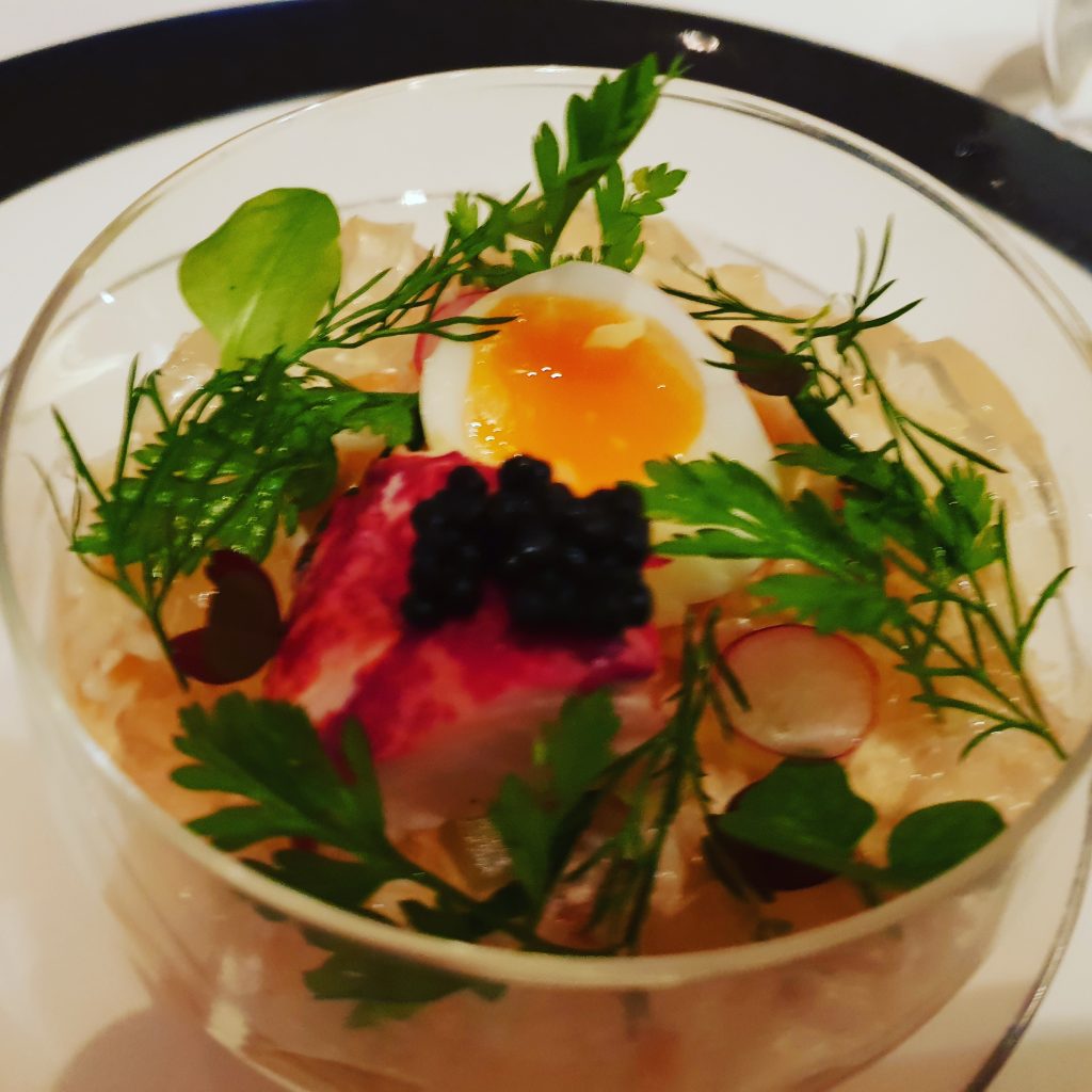 Glass bowl, with eggs, black caviar, aspic jelly and green leaves of herbs. 