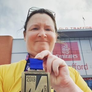 Me outside Old Trafford, holding up my Manchester Marathon medal