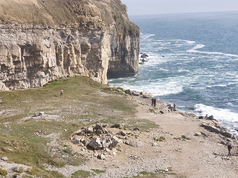 View of sea cliffs and sea, with climbers in the back ground