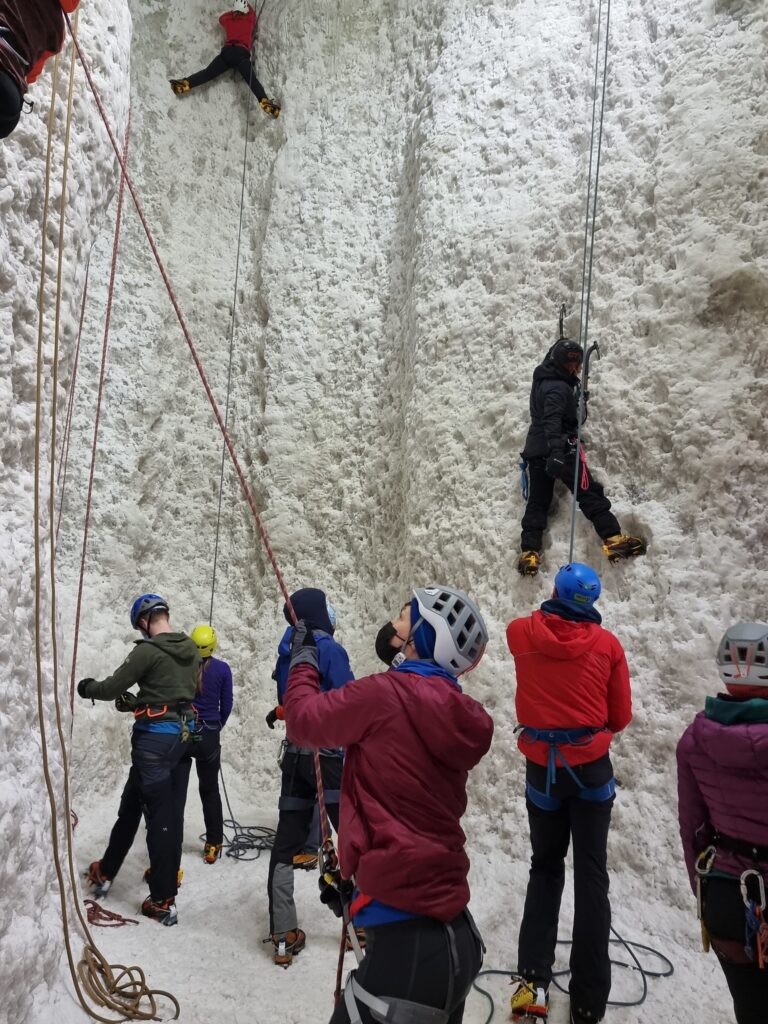 Indoor ice walls, with people holding ropes and climbing the walls