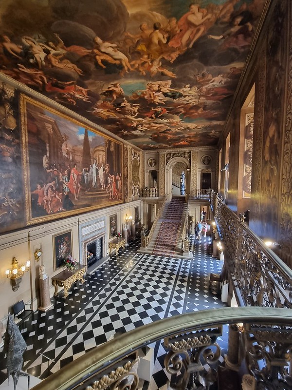 view from balcony at Chatsworth. Floor is black and white tiles. walls are covered in classic paintings. 