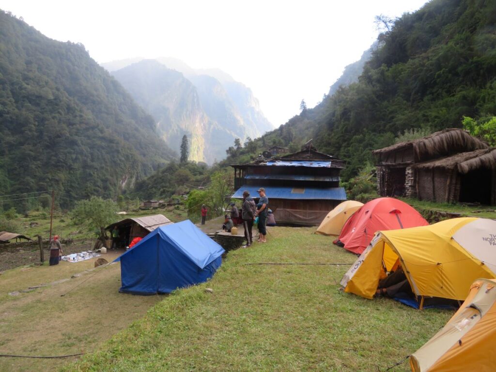 Terraces and tents, mountains in the background. Team members standing around