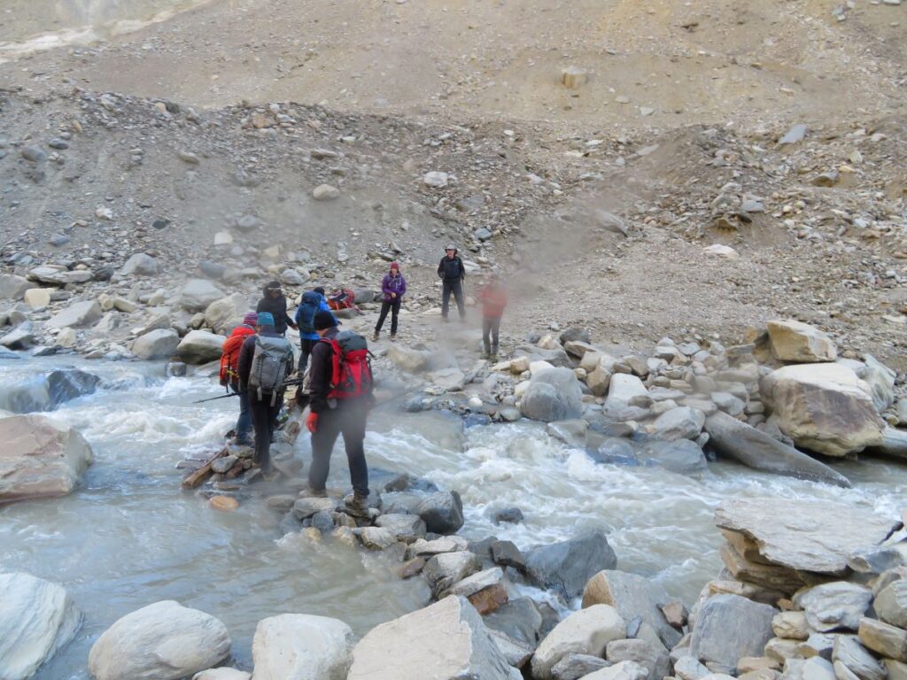 The team walking across a set of rocks in a river
