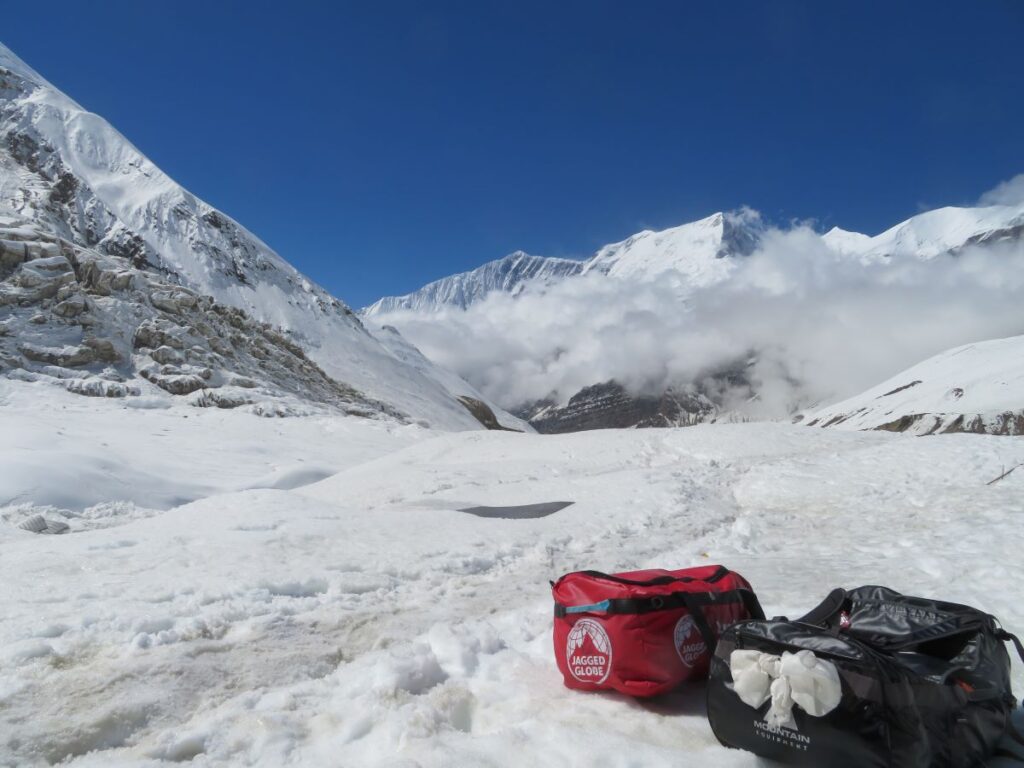 2 kit bags on the snow, with a background of mountains and blue sky