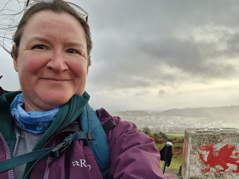 Selfi on top of a hill - trig marker behind me with a red welsh dragon