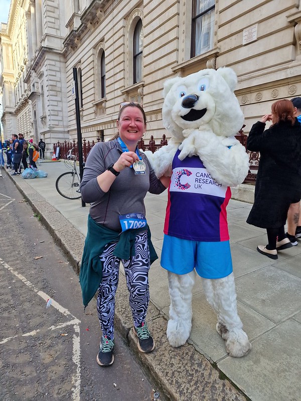 Me holding up my Winter Run Medal, next to a man in a Polar bear costume